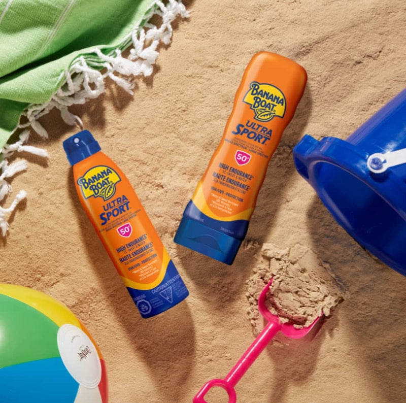 Banana Boat Ultrasport sunscreen products resting in the sand on a beach.